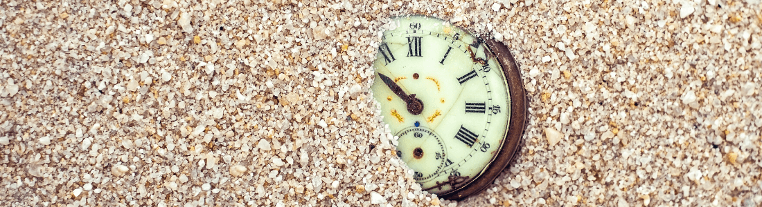 Old pocket watch partially covered with sand